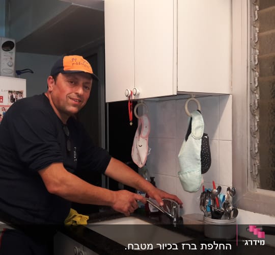 אדם מתקן ברז במטבח עם כלים